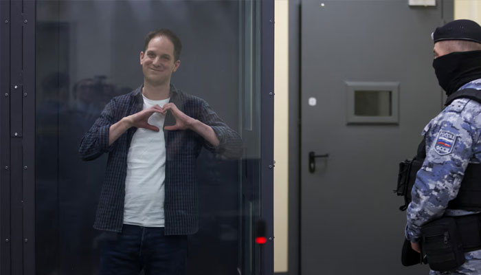 Wall Street Journal reporter Evan Gershkovich, who is in custody on espionage charges, makes a heart-shaped gesture inside an enclosure for defendants before a court hearing in Moscow, Russia, April 23. —Reuters