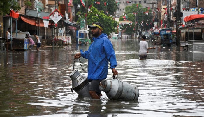 A man with milk-canisters walks along a flooded street, following rains during the monsoon season in Hyderabad, August 24, 2022. — Reuters