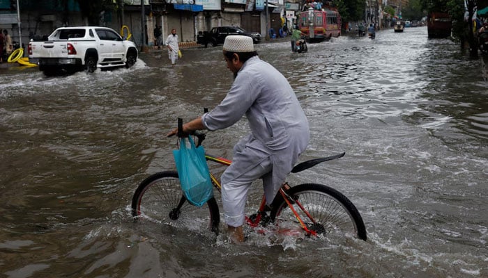 A man rides bicycle along a flooded road, following heavy rains during the monsoon season in Karachi, July 25, 2022. — Reuters