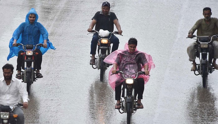 Motorcyclists on the way wear plastic sheet to protect themselves from rain in Karachi on July 30, 2024. — INP