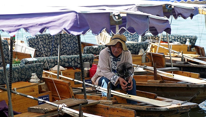 A boatman holds a portable fan as he waits for customers in a boat on the West Lake, amid a red alert for heatwave in Hangzhou, Zhejiang province, China August 2, 2024. — Reuters