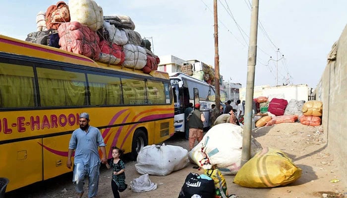 People load their belongings onto a bus at the Karachi bus terminal in Sindh on October 27, 2023. — AFP