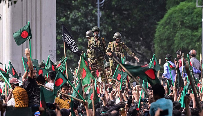 Anti-government protestors march towards Prime Minister Sheikh Hasinas palace as army personnel stand guard in Shahbag area, near Dhaka university in Dhaka on August 5, 2024. — AFP