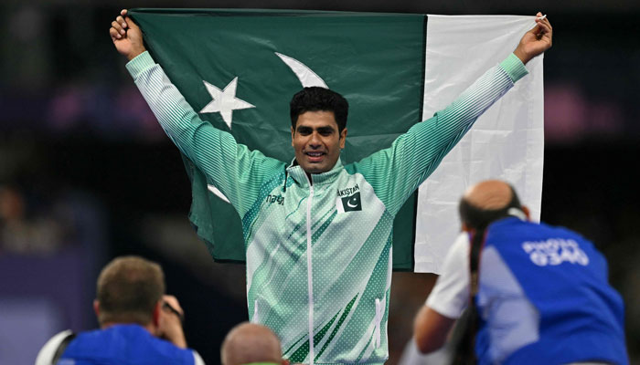 Gold medallist Pakistans Arshad Nadeem poses with national flag in front of photographers as he celebrates winning the mens javelin throw final of the athletics event at the Paris 2024 Olympic Games at Stade de France in Saint-Denis, north of Paris, on August 8, 2024. — AFP