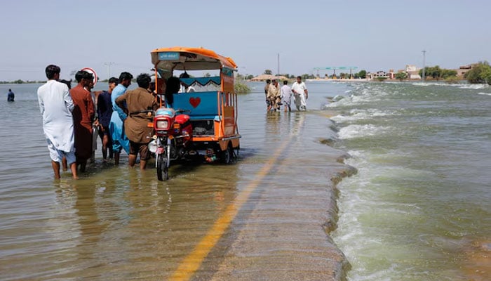 Displaced people stand on flooded highway, following rains and floods during the monsoon season in Sehwan, Pakistan, September 16, 2022. — Reuters