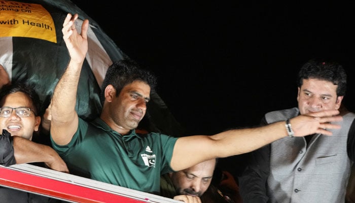 Arshad Nadeem, Pakistan’s first Olympic gold medalist athlete in the mens javelin, waves from the roof of a vehicle to fans who gathered to welcome him on his arrival, outside the Allama Iqbal International Airport, in Lahore on August 11, 2024. — Reuters