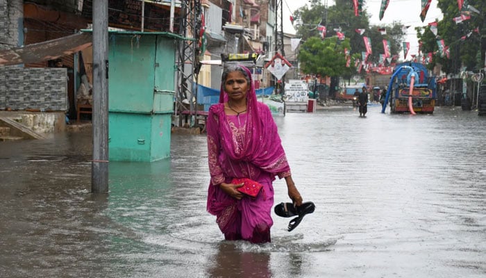 A woman wades through a flooded road in Hyderabad. — Reuters/File