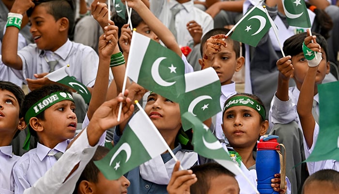 Students wave Pakistan۔s national flag during Independence Day celebrations at the mausoleum of founding father Quaid-e-Azam Mohammad Ali Jinnah in Karachi on August 14, 2024. — AFP