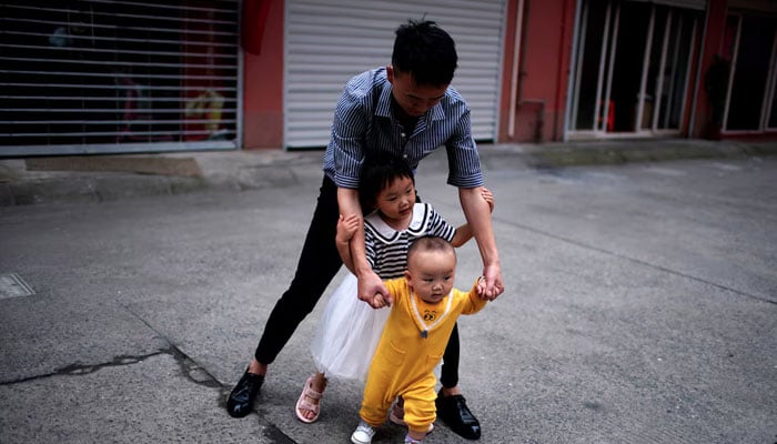 Sun Yans husband plays with their two children on the outskirts of Shanghai, China June 3, 2021. — Reuters