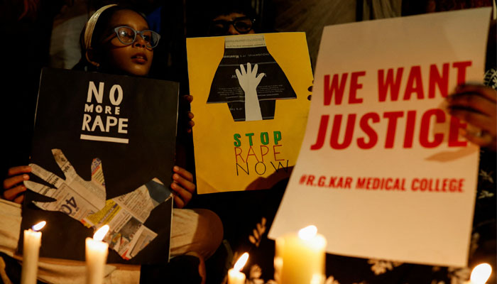 People hold posters during a vigil condemning the rape and murder of a trainee medic at a government-run hospital in Kolkata, on a street in Mumbai, India, August 14, 2024. — Reuters