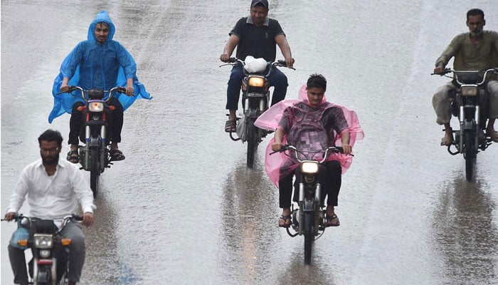 Motorcyclists ion the way wear plastic sheet to protect from rain in Karachi on July 30, 2024. — INP