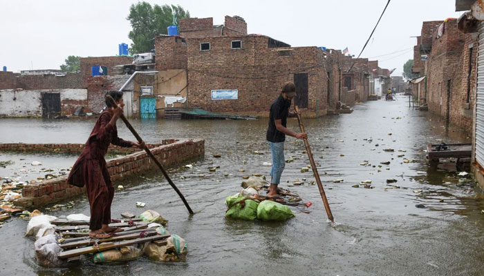 Men paddle on makeshift rafts as they cross a flooded street in Hyderabad in an undated picture. – Reuters