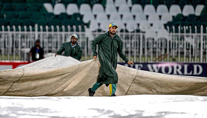 Groundmen cover the pitch owing to dark clouds as poor light halts play during the fourth day of the second and last Test cricket match between Pakistan and Bangladesh at the Rawalpindi Cricket Stadium in Rawalpindi on September 2, 2024. — AFP