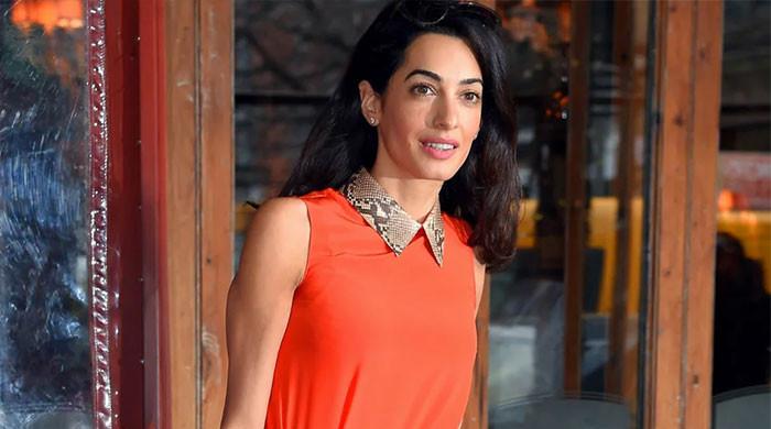 Amal Clooney wows in an orange jumpsuit with George Clooney as she leaves Venice