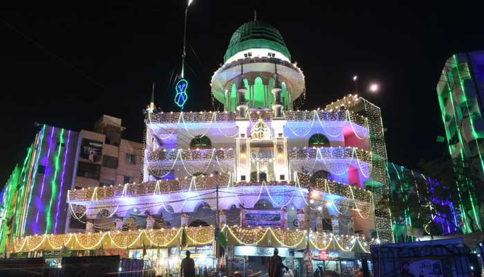 Muslims stand outside an illuminated mosque during celebrations marking the Eid Milad un Nabi in Karachi on November 29, 2017. — AFP