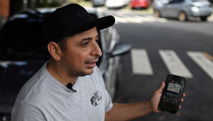 Taxi driver Napoleon Osorio shows an app on his phone that he uses to charge his rides in bitcoins in San Salvador on September 4, 2024. — AFP