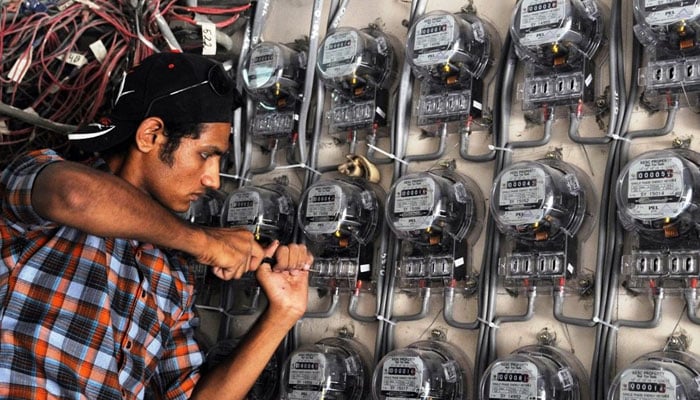 A technician fixes new electricity meters at a residential building in Pakistan. — AFP/File