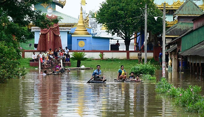 Flood-affected residents ride bamboo rafts while others gather on higher ground by a temple in Taungoo, Myanmar´s Bago region on September 14, 2024, following heavy rains in the aftermath of Typhoon Yagi. — AFP