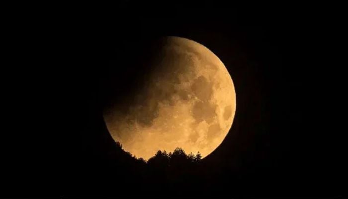 A lunar eclipse occurring as a shadow falls on the moon seen through a telescope. — AFP/File