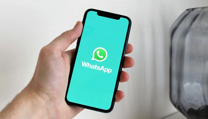 A representational image shows the WhatsApp logo displayed on a phone screen. — Pexels