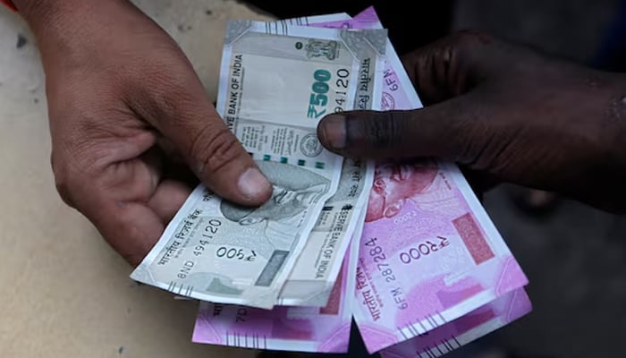 A customer hands Indian currency notes to an attendant at a fuel station in Mumbai, India on August 13, 2018. — Reuters