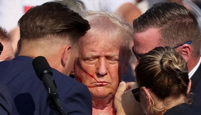 Republican presidential candidate and former US President Donald Trump with his bloodied face is assisted by the Secret Service during a campaign rally at the Butler Farm Show in Butler, Pennsylvania, US, July 13, 2024. — Reuters