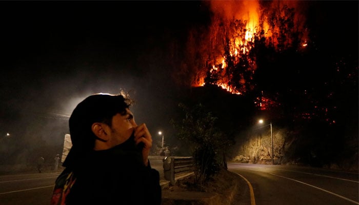 A man covers his mouth with his shirt as a hill burns behind him during a wildfire in Quito on September 24, 2024. — AFP