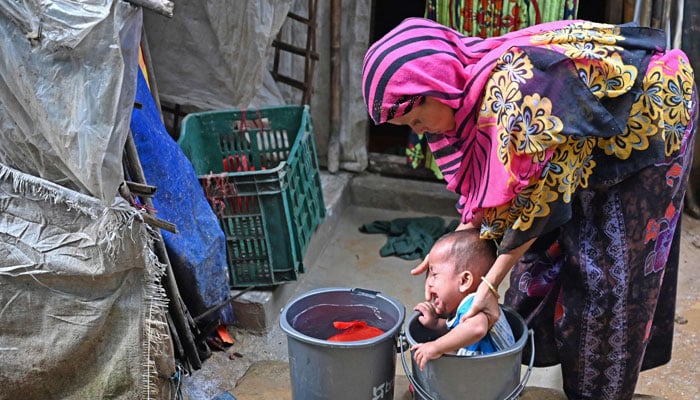 A Rohingya refugee bathes her child at Kutupalong refugee camp on September 9, 2024. — AFP