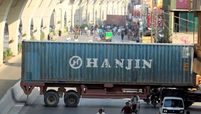 A representational image showing commuters passing through a road blocked by containers. — Reuters/File