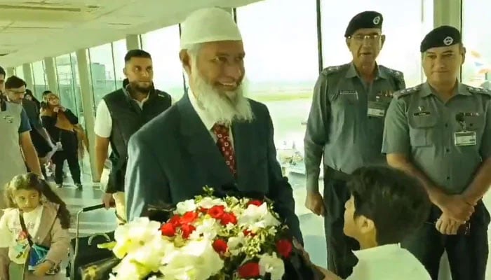 Islamic scholar and public speaker Dr Zaik Naik is greet with a bouquet of flowers upon his arrival at the Islamabad airport on September 30, 2024. — Screengrab via X/@asadnasir2000