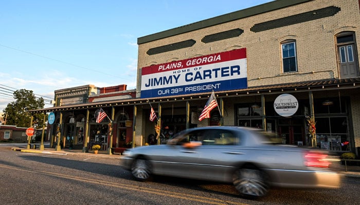 A car drives past a sign reading Home of Jimmy Carter in Plains, Georgia, on September 30, 2024. — AFP