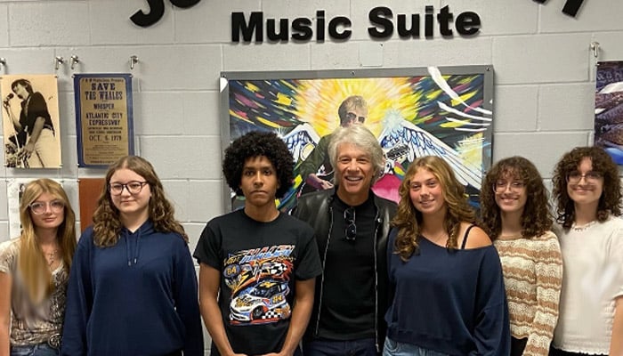 Jon Bon Jovi poses alongside the students in front of the mural they painted to honour him