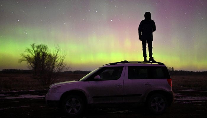 A person stands on a car while looking at Auroras, caused by a coronal mass ejection on the sun, that illuminate the skies in the southwestern Siberian Omsk region, Russia on November 6, 2023. — Reuters