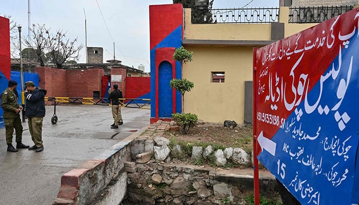 Police personnel stand guard near a signboard reading police check post Adiala at the entrance of Adiala jail in Rawalpindi on January 31, 2024. — AFP