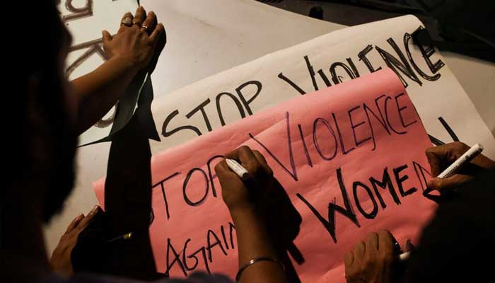 People write slogans on posters before the start of a candlelight vigil condemning the rape and murder of a trainee medic at a government-run hospital in Kolkata, on a street in Mumbai, India on August 14, 2024. — Reuters