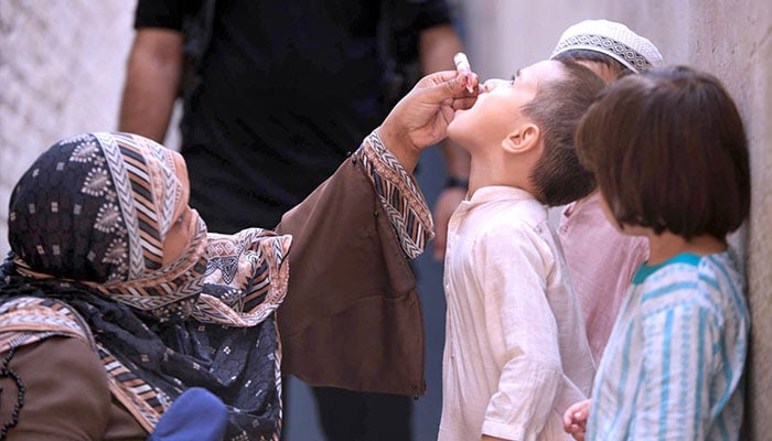 Female polio worker administering polio drops to children at Warsak road during anti-polio vaccination campaign in Peshawar on September 9, 2024. — APP