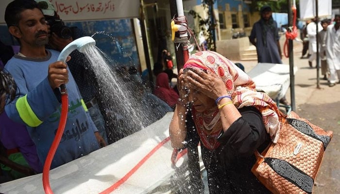 In this undated photo, a volunteer showers a woman with water during a heat wave in Karachi. — AFP/File