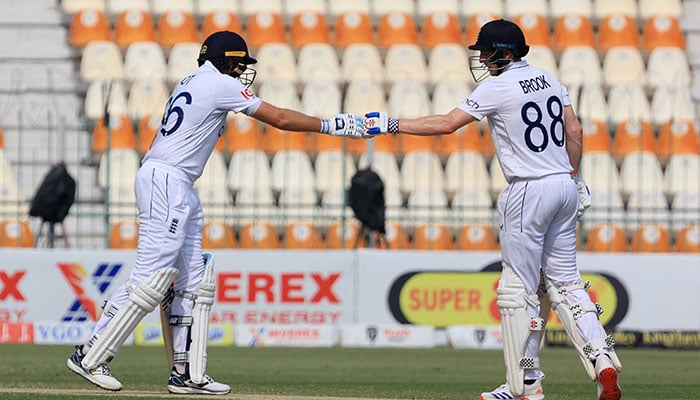 Englands Harry Brook and Joe Root bump fists during their innings on the third day of the first Test against Pakistan at Multan Cricket Stadium on October 9, 2024. — Reuters