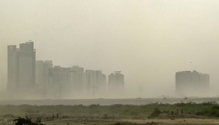 A dust storm envelopes buildings in Karachi on October 10, 2024. — AFP