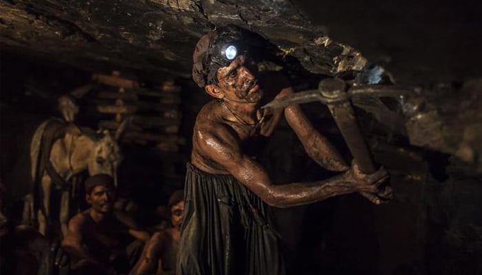 Workers at a coalmine dig the sedimentary rock with pick axes. —Reuters/ File