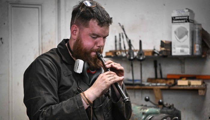 Artisan bagpipe maker Ruari Black tests a bagpipe chanter in the workshop of Kilberry Bagpipes in Edinburgh, on October 7, 2024. — AFP