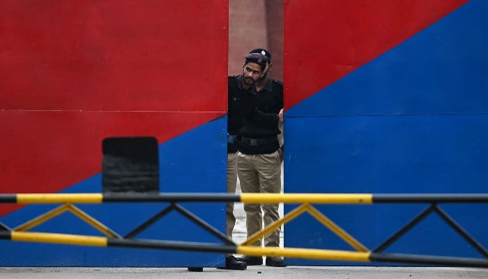 A policeman peeps through the main gate of the Adiala jail in Rawalpindi on January 30, 2024. —AFP