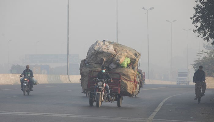 A man rides a motor tricycle, loaded with sacks of recyclables, amid dense smog in Lahore November 24, 2021. — Reuters