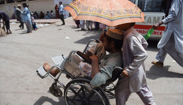 This photo shows a boy helping a patient outside a hospital during a heatwave in Karachi. — AFP/File