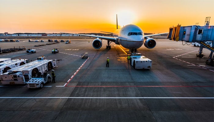 A representational image showing workers towing an aircraft on a runway. — Unsplash