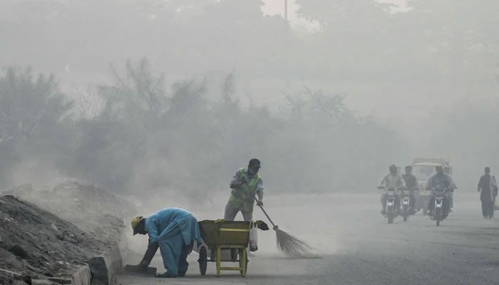 Commuters make their way through a road amid smoggy conditions in Lahore on October 23, 2024. — AFP