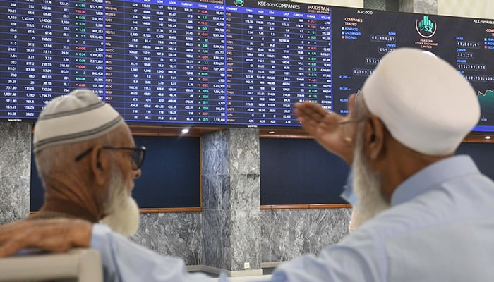 Brokers discuss as they look at an index board showing the latest share prices at the PSX in Karachi on November 28, 2023. — Online