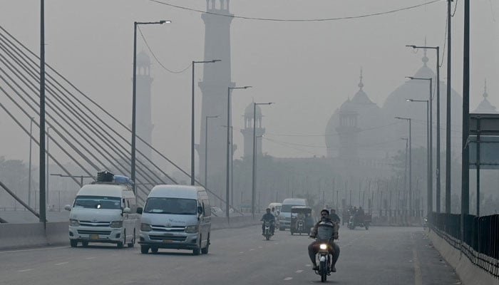 Commuters drive along a road amid heavy smog in Lahore on October 29, 2024. — AFP