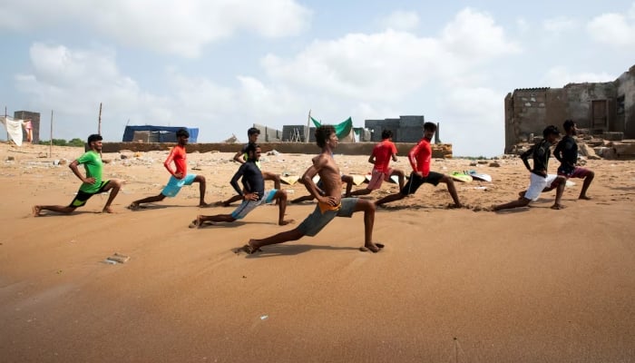 Surfers warm up and stretch as they prepare to surf at Turtle Beach in Karachi on September 4, 2024. —Reuters