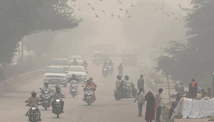 People and vehicles are seen on a road amidst the morning smog in New Delhi, India, November 8, 2023. — Reuters